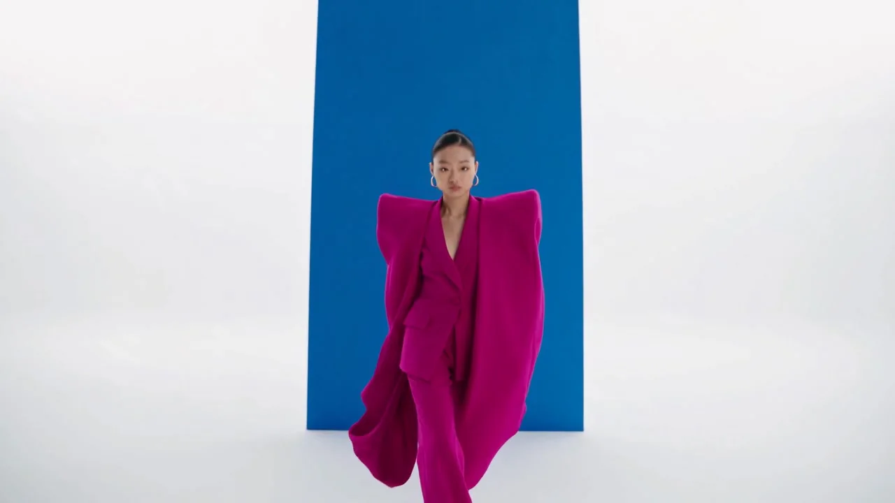 선명한 파란색과 흰색 배경 앞의 하늘거리는 자홍색 옷차림의 여성